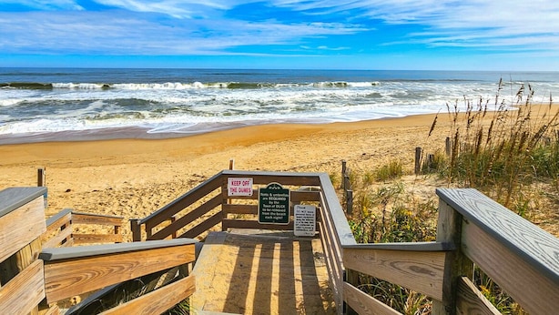 A wooden boardwalk leading to a beach with a sign indicating 'Keep off the dunes' and 'No swimming'. - DUCK DUCHESS - Gorgeous, Spacious 5 BR home w/Private Pool and Rec Room (Duck)