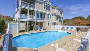 A two-story building with a swimming pool, outdoor seating, and a fenced deck. - DUCK DUCHESS - Gorgeous, Spacious 5 BR home w/Private Pool and Rec Room (Duck)