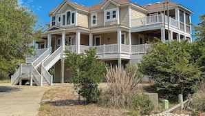 A two-story house with a balcony, a staircase, and a well-maintained lawn. - DUCK DUCHESS - Gorgeous, Spacious 5 BR home w/Private Pool and Rec Room (Duck)