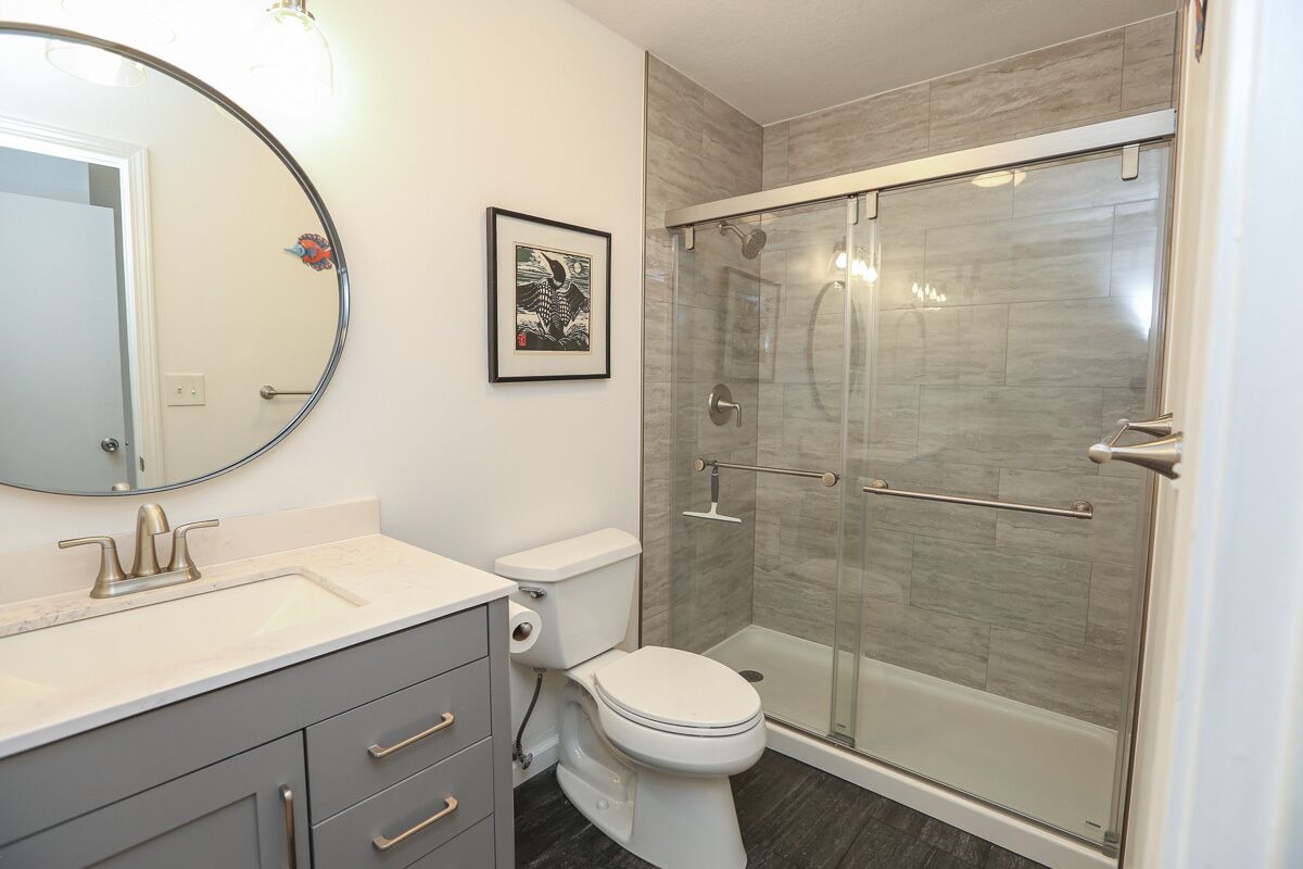 A bathroom with a toilet, sink, and a glass-enclosed shower.