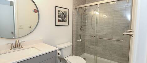 A bathroom with a toilet, sink, and a glass-enclosed shower.
