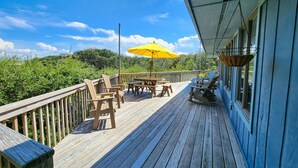 A wooden deck with outdoor seating and a yellow umbrella. - Tara - Enjoy easy beach access from this Traditional 3 BR Beach Cottage in Southern Shores (Southern Shores)