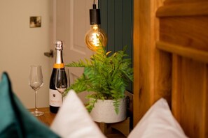 Une bouteille de vin, un verre et une plante en pot sur une table en bois.
