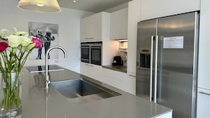 Una cucina moderna con elettrodomestici in acciaio inossidabile, lavello integrato e lampada a sospensione.