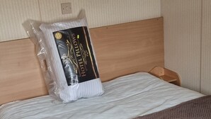 En säng med en huvudgavel i trä, en brun filt och en kudde i en plastpåse.
