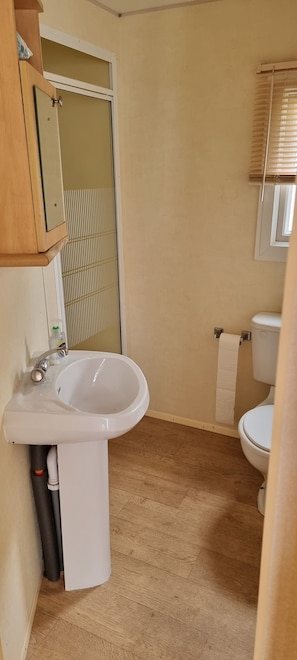 A bathroom with a sink, toilet, and a window with blinds. - 8 Berth Caravan Direct Beach Access (Skegness)