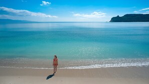 A woman standing on a beach with a view of the sea and a distant mountain. - Self-contained beach house in Sardinia, 5 minutes from the beach (Quartu Sant'Elena)