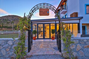 En hotelindgang med en stentrappe, plantekasser og et skilt der viser "Thomas Suites DATCA".