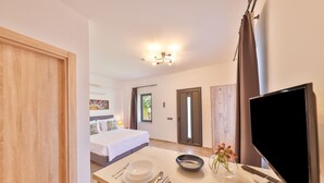 Een hotelkamer met een bed, een zithoek met een tafel gedekt voor twee personen, een televisie en een badkamer op de achtergrond.