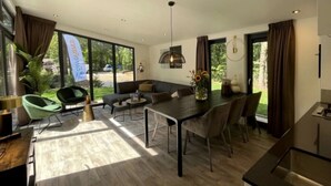 A modern interior with a dining area, seating, and large windows.