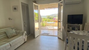 A room with a sofa, a television, and a balcony with a table and chairs.