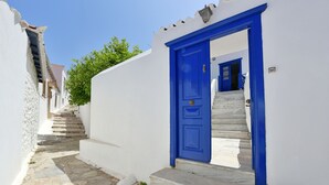 A narrow stone-paved alley with a blue door leading to a staircase. - Bexis Residences Hydra (Hydra)