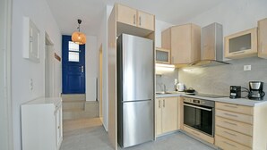 A modern kitchen with a stainless steel refrigerator, wooden cabinets, a built-in oven, and a coffee maker. - Bexis Residences Hydra (Hydra)