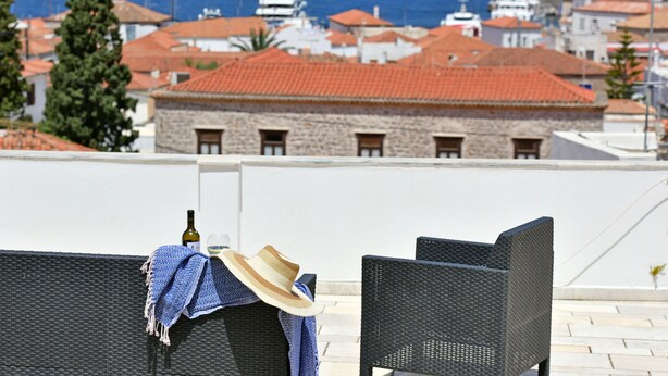 A terrace with wicker chairs, a bottle, and a hat. - Bexis Residences Hydra (Hydra)