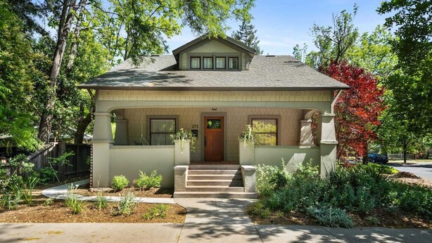A two-story house with a front porch, a small garden, and a driveway.