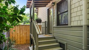 A residential house with a wooden deck, a staircase leading to the front door, and a potted plant on the porch.