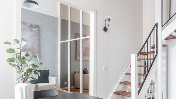 A modern dining area with a round table, black chairs, and a potted plant. - Stylish Historical Loft with Sauna & Free Parking (Tampere)