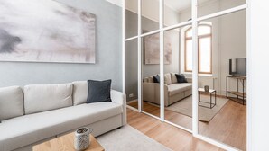 A modern living room with a sofa, a coffee table, and a TV stand. - Stylish Historical Loft with Sauna & Free Parking (Tampere)