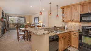 A kitchen with granite countertops, wooden cabinets, a dishwasher, and a stove. - Prime Avon Location | Walk to Gondola & Dining | River Trail Access & Views (Avon)