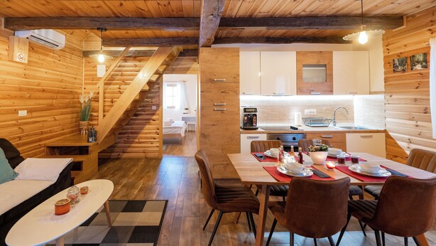 A cozy cabin-style interior with a dining area, kitchen, and staircase. - Chalet Markoci With Hot Tub (Rakovica)