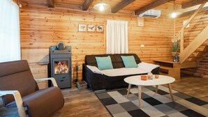A cozy log cabin interior with a sofa, armchair, and a small table. - Chalet Markoci With Hot Tub (Rakovica)