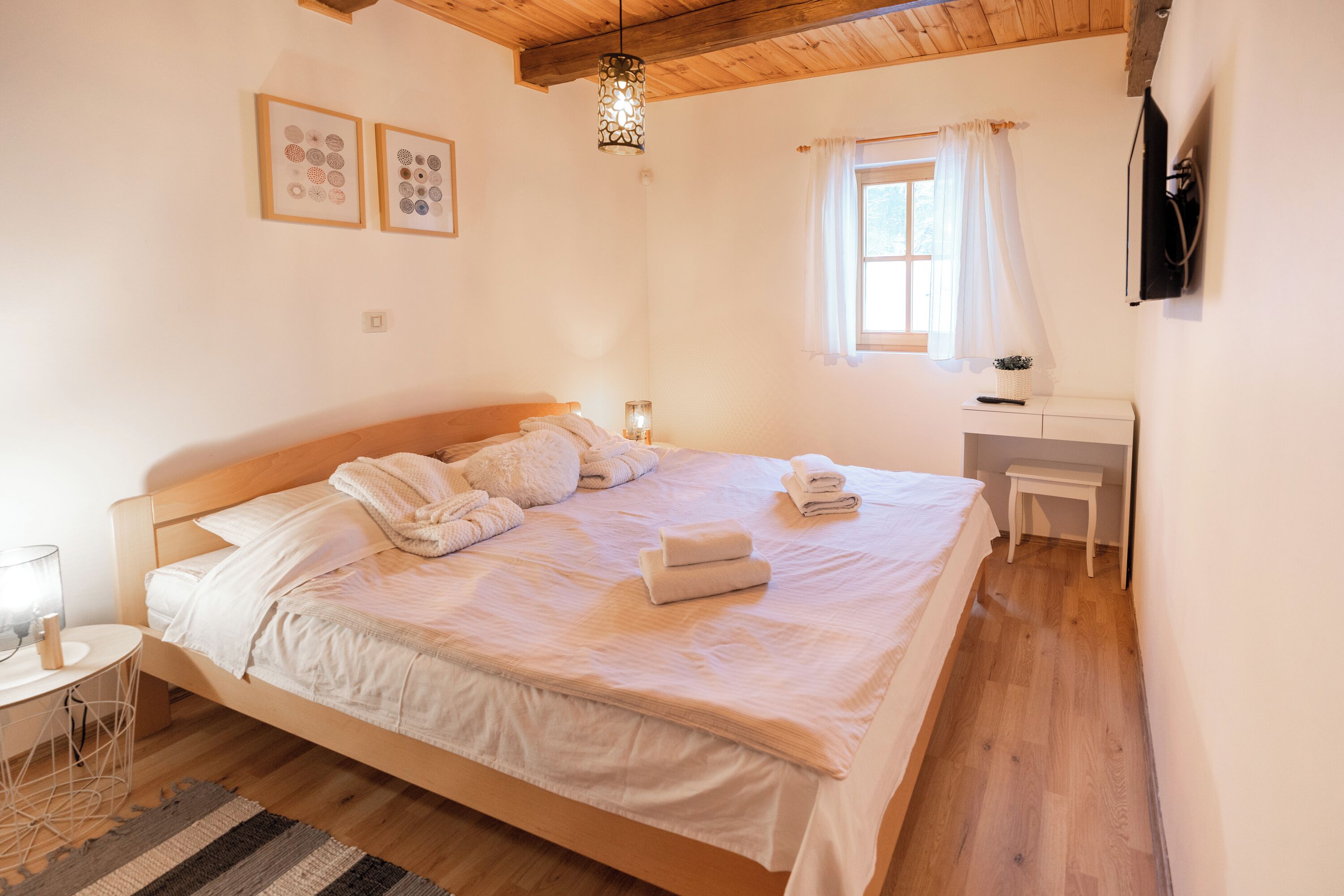 A bedroom with a wooden bed, bedside table, and a window with curtains.