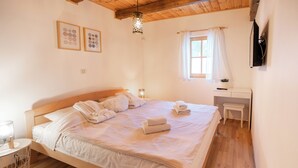 A bedroom with a wooden bed, bedside table, and a window with curtains. - Chalet Markoci With Hot Tub (Rakovica)