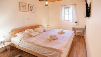 A bedroom with a wooden bed, bedside table, and a window with curtains.