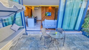Un espace extérieur moderne aménagé avec un canapé, des fauteuils et une table, qui donne accès à une pièce équipée d’un téléviseur et d’un canapé.