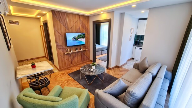 Un salon moderne avec un canapé, une table à manger et un téléviseur fixé au mur.