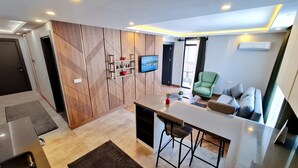 Un salon moderne avec un téléviseur, un fauteuil vert et un canapé.