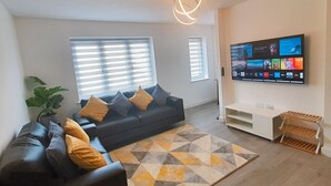 A modern living room with a sofa, a TV mounted on the wall, and a geometric patterned rug.