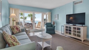 Una sala de estar con sofá, sillones, televisor y vistas al exterior.