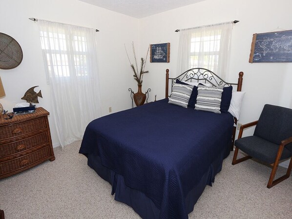 Un dormitorio con una cama grande, un aparador de madera, una silla y un mapa en la pared.