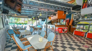En restaurant med skakternet gulv, blå polstrede stole og borde med hvide dugge.