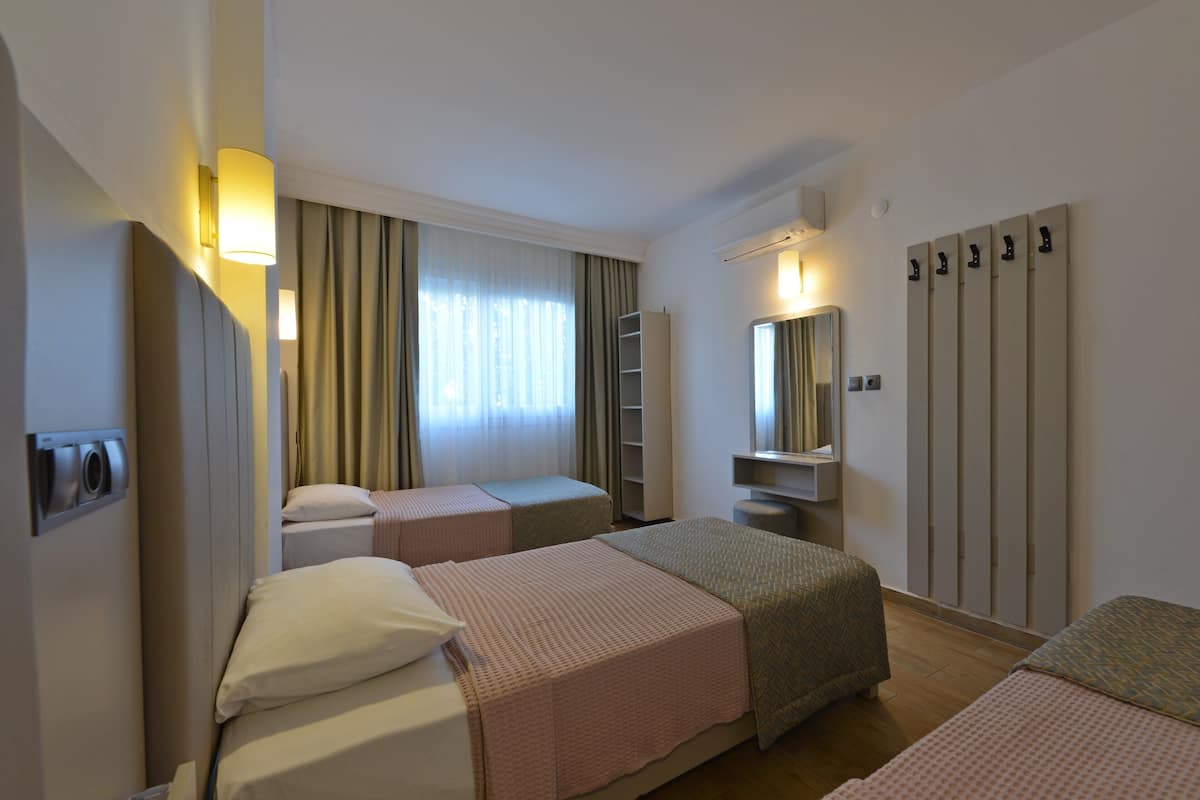 Ett hotellrum med två sängar, en garderob, en spegel och ett litet skrivbord.