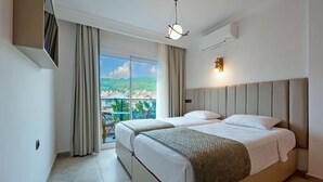 Et hotelværelse med en stor seng, en balkon med udsigt over byen og en moderne lampe.