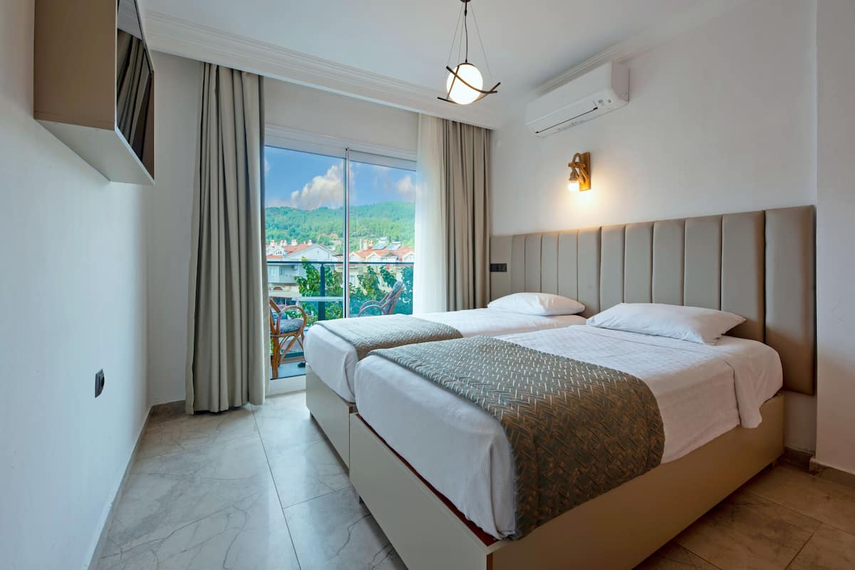 Ett hotellrum med en stor säng, en balkong med utsikt över staden och en modern lampa.