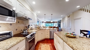 A modern kitchen with stainless steel appliances, a granite countertop, and a central island. - Beach Club Villa-Oceanviews in Wild Dunes- community pool & screened porch! (Isle of Palms)