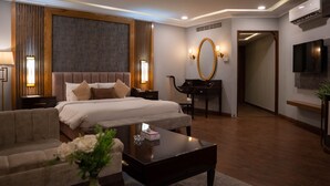 Une chambre d’hôtel moderne équipée d’un grand lit, d’un bureau, d’une chaise, d’une télévision et d’un miroir.