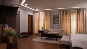 Une chambre d’hôtel moderne avec un plancher en bois, un canapé, un lit, une table basse et un tableau au mur.