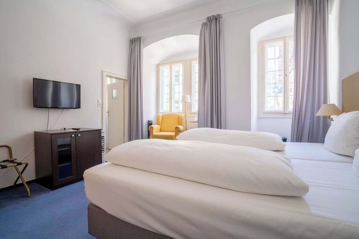 A hotel room with a bed, a television, a desk, and a chair.