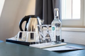 A table with a bottle of water, two glasses, and a tray of coffee cups. - Hotel zum Ritter St. Georg (Heidelberg)