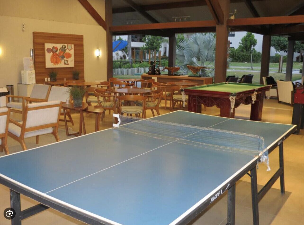 A billiards room with a pool table, multiple chairs, and a table tennis table.