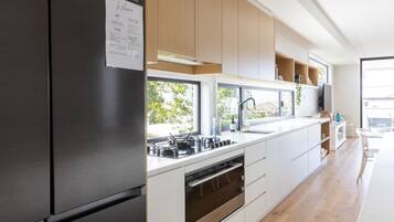 A modern kitchen with a stainless steel refrigerator, white cabinetry, and a built-in oven.