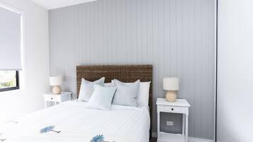 A bedroom with a bed, two nightstands, and a window.