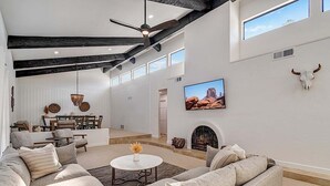 A spacious living room with a high ceiling, a fireplace, a television, and a bull skull decoration. - Amazing- Pool Home- Fire Pit & Ping Pong Table (Mesa)
