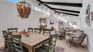 A spacious interior with a wooden dining table, green chairs, a patterned sofa, and a ceiling fan. - Amazing- Pool Home- Fire Pit & Ping Pong Table (Mesa)