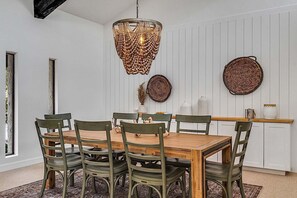 A dining area with a wooden table and six chairs, a woven pendant light, and two woven wall decorations.