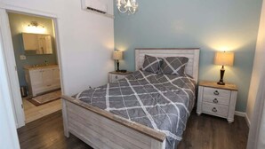 A bedroom with a bed, bedside tables, a chandelier, and a mirror.